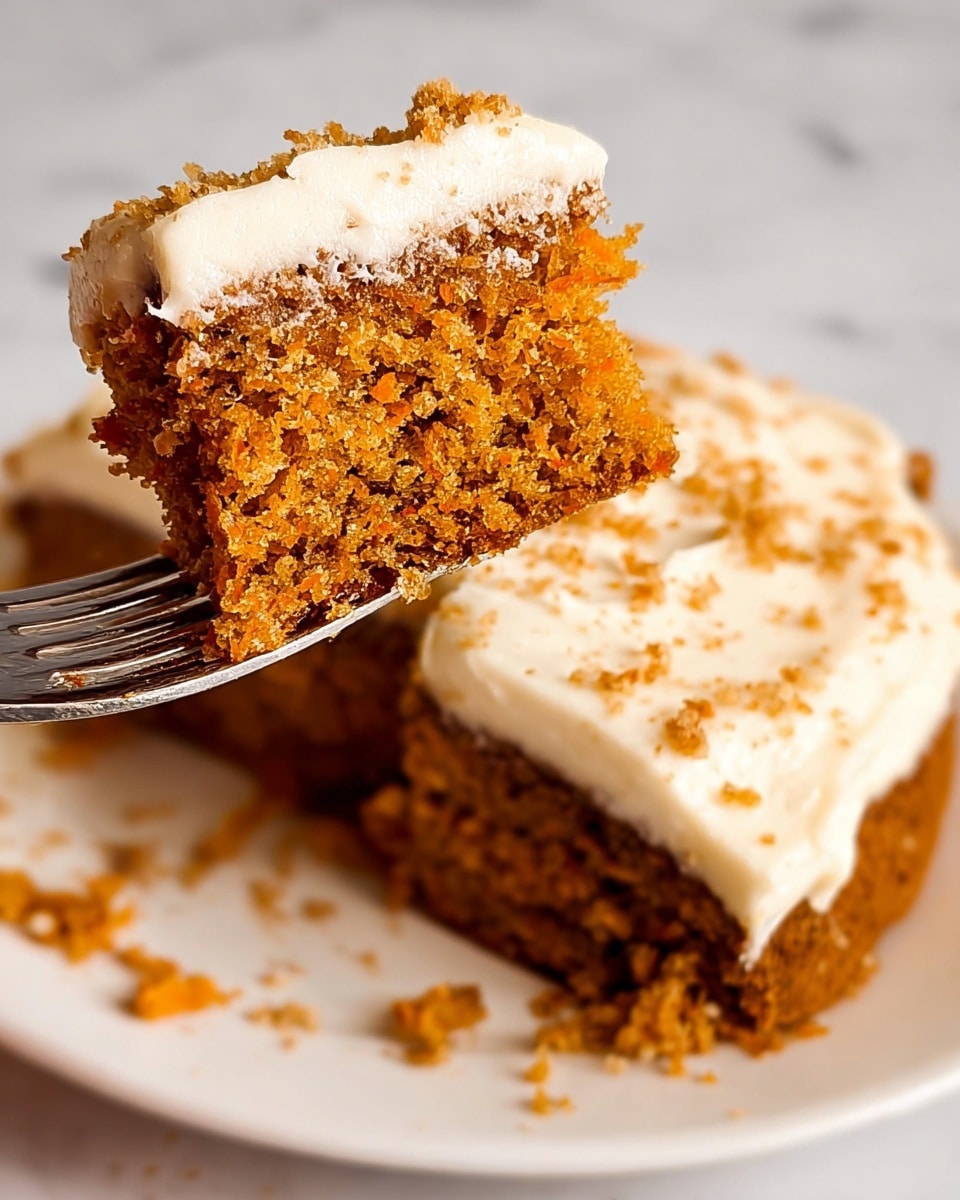 A close-up of a two-layer carrot cake with a thick layer of white cream cheese frosting on top and between the layers. The cake layers are brown with visible small orange carrot bits and some nut pieces mixed in, showing a moist and crumbly texture. The frosting is smooth with slight swirls and covers the top and sides partially, blending into the cake edges. The cake sits on a silver tray placed on a white marbled textured surface. photo taken with an iphone --ar 4:5 --v 7