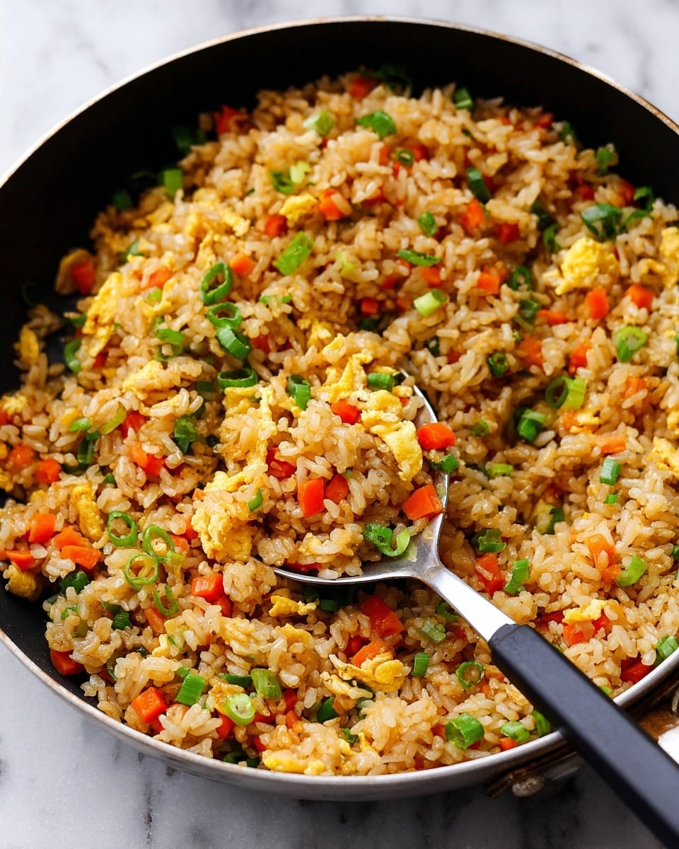 A black pan filled with fried rice that has three main layers: the base layer of light brown cooked rice mixed with small pieces of bright orange carrots, the middle layer of soft scrambled eggs torn into small fluffy yellow pieces, and the top layer sprinkled with chopped green onions for a fresh green touch. A spoon with a black handle is partly buried in the rice, lifting a mix of all the ingredients. The pan is placed on a white marbled surface. Photo taken with an iphone --ar 4:5 --v 7