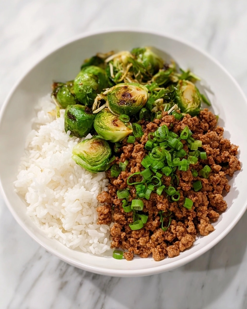 A white bowl contains three main layers: the bottom layer is fluffy white rice, the middle layer is a generous amount of brown, cooked ground meat with a slightly moist texture, and the top layer is chopped fresh green onions sprinkled all over the meat. On one side inside the bowl, there are green, cooked Brussels sprouts that are cut in half and mixed with thin, slightly browned strands of cooked vegetables. The bowl is placed on a white marbled surface. Photo taken with an iphone --ar 4:5 --v 7