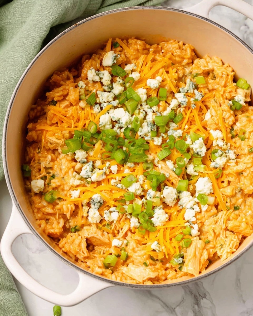 A large white pot filled with a creamy orange rice dish mixed with small pieces of greenbell pepper and chicken chunks. On top, there are shredded bright yellow cheddar cheese and scattered crumbled white blue cheese with green veining. Sliced green onions are sprinkled over everything, adding a fresh green color contrast. The pot sits on a white marbled surface with a soft green cloth blurred in the background. photo taken with an iphone --ar 4:5 --v 7