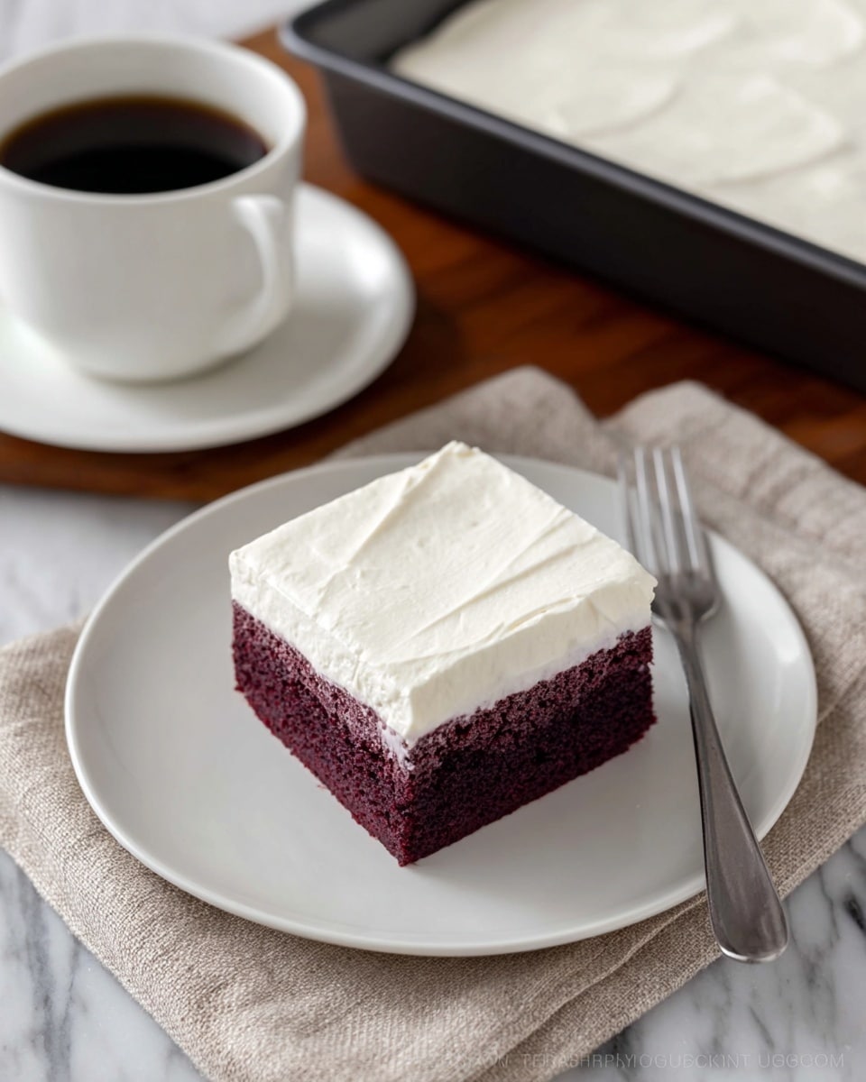 A square piece of dessert with two visible layers sits centered on a white plate. The bottom layer is a thick, moist, dark purple cake with a porous texture. The top layer is a smooth, creamy white frosting that evenly covers the cake layer beneath it. The surface of the frosting is mostly flat with gentle, soft swirls and a slightly velvety texture. The white plate rests on a beige fabric, with a blurred white cup and saucer in the background over a white marbled texture. photo taken with an iphone --ar 4:5 --v 7