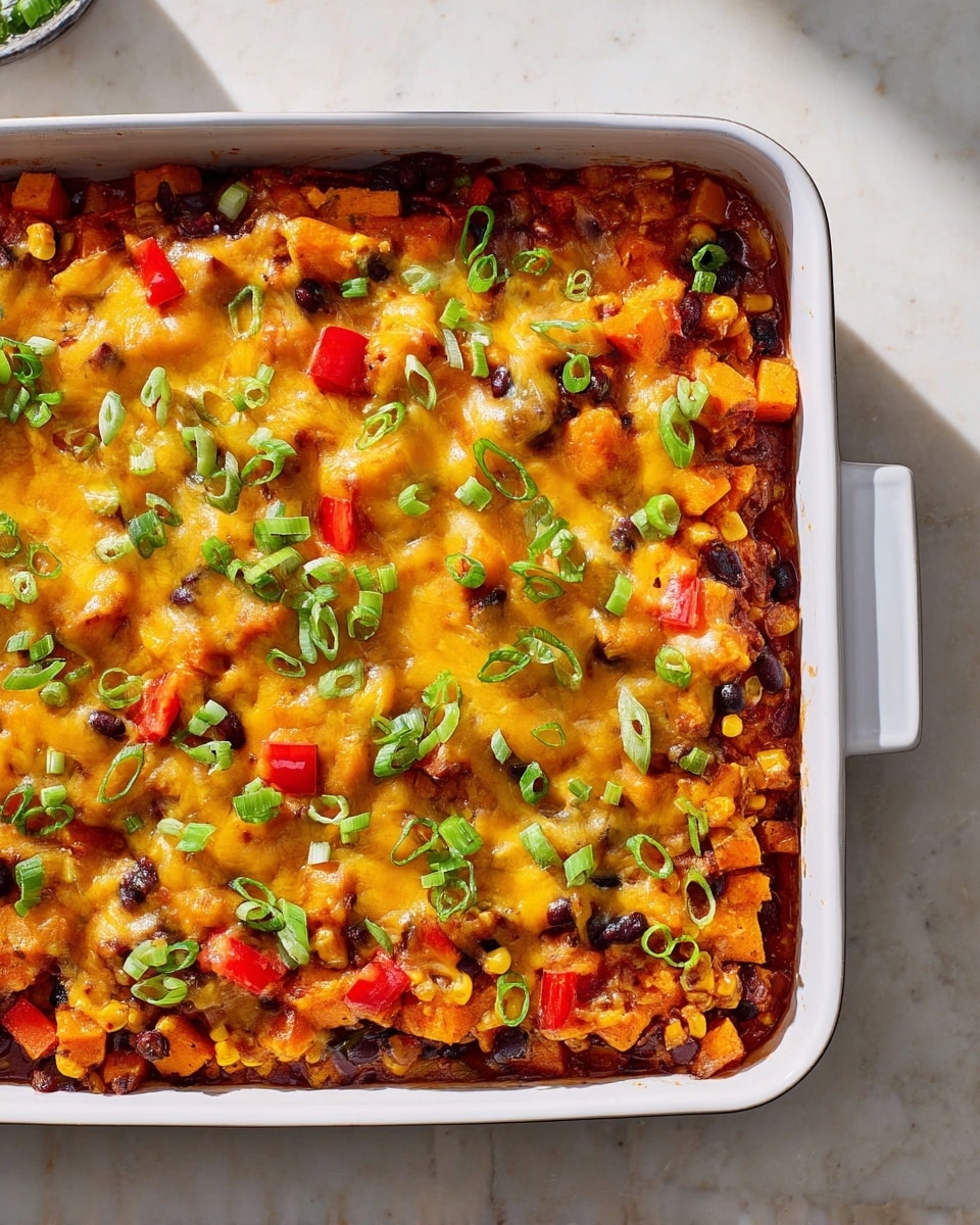 A white rectangular baking dish filled with a layered casserole is shown. The bottom layer is a rich red sauce with visible corn kernels and black beans mixed in. On top of this is a layer of diced orange sweet potatoes and chunks of red bell peppers scattered throughout. The entire dish is covered with melted yellow and light orange cheese, which has a bubbly texture. Bright green, thinly sliced scallions are sprinkled evenly over the cheese, adding a fresh contrast. The dish sits on a white marbled surface with natural light coming from the top left. Photo taken with an iphone --ar 4:5 --v 7