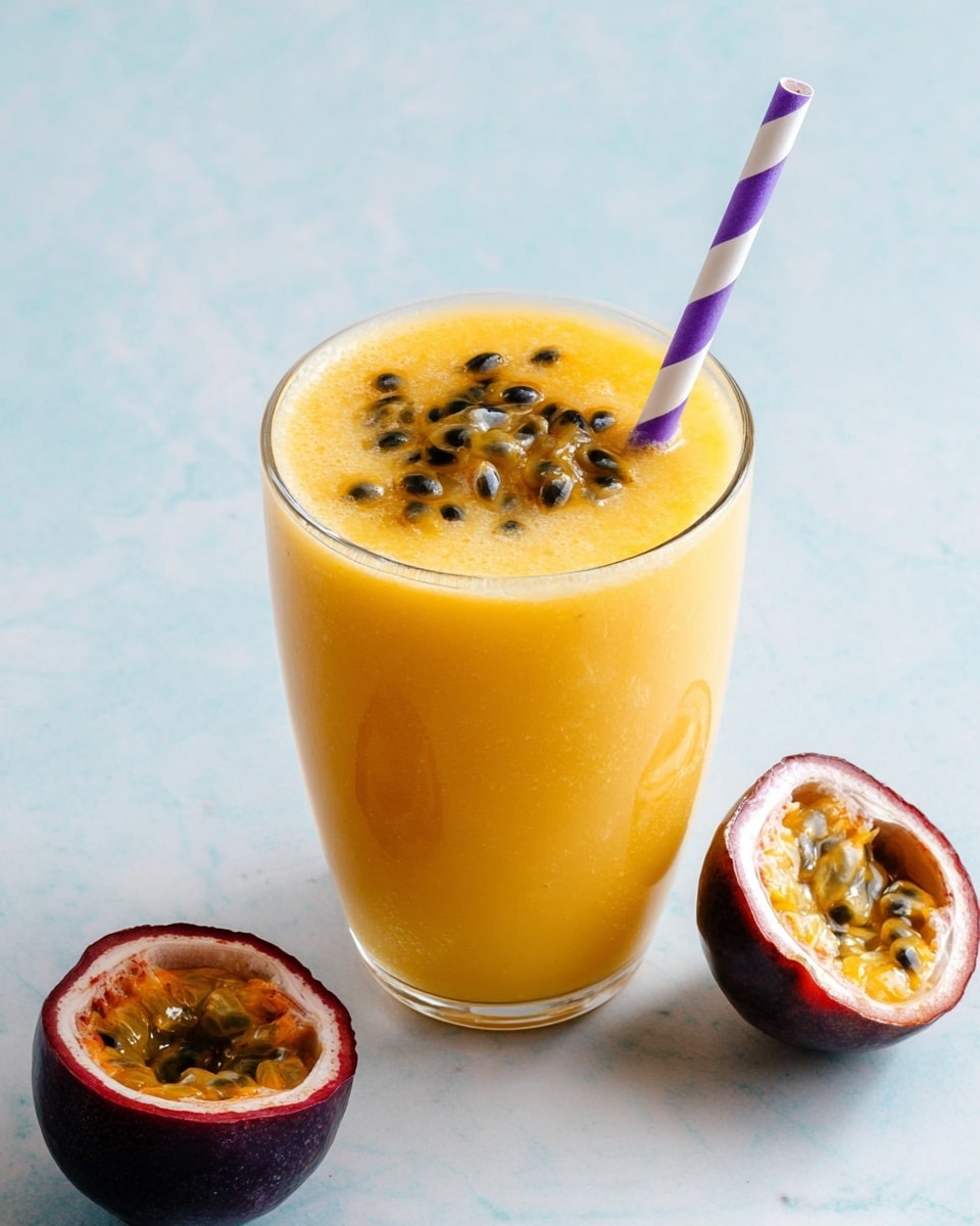 A clear glass is filled with a smooth, bright yellow-orange passion fruit smoothie. On top, there is a layer of glossy passion fruit seeds and pulp, adding a textured, dark, and shiny contrast. A purple and white striped straw is inserted into the smoothie near the edge. To the side on a white marbled surface, there is a halved passion fruit showing its dark purple skin and vibrant yellow pulp with black seeds inside. Photo taken with an iphone --ar 4:5 --v 7